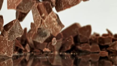 Chunks of Chocolate Falling onto Reflective Surface