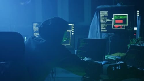Un misterioso hacker trabaja activamente en un entorno con poca luz centrado en las tareas