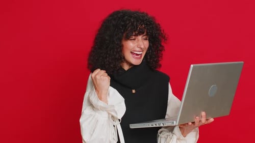 Woman Celebrates Good News While Holding Laptop