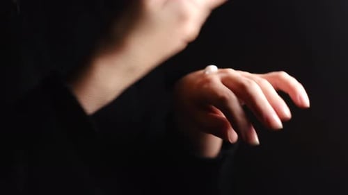 Woman applying hand cream on dark background