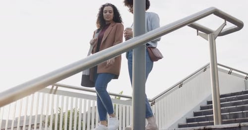 Two Stylish Women Walk Down Outdoor Staircase Talking