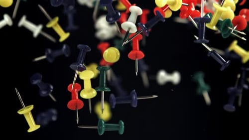 Colorful Push Pins Falling in Slow Motion on Black