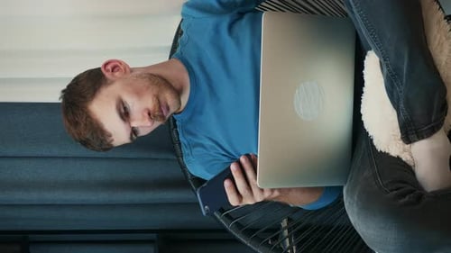Man Relaxes with Laptop and Phone at Home