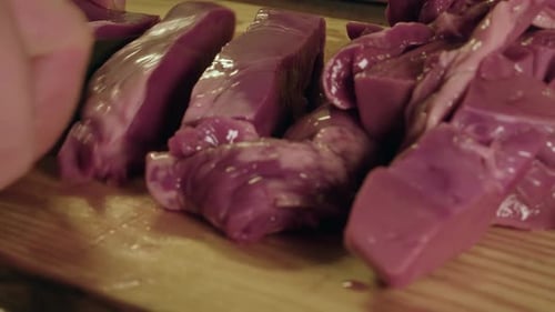 Close up view: Raw organ meat, pig heart, sliced on wooden chop block