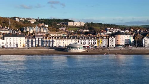 Beautiful drone footage of Aberystwyth town at sunset, showcasing the promenade, bandstand, and stun