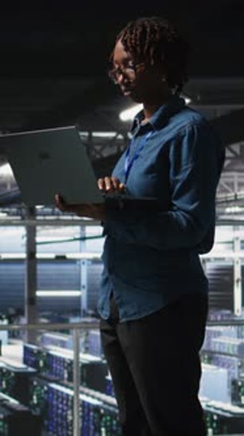 Vertical Video Data Center System Administrators Doing Maintenance Tasks on Laptop