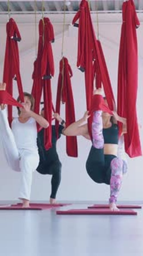 Women stretching with aerial yoga red hammocks