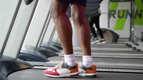 Young Man Running on Treadmill at Gym Close Up of Legs