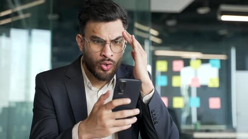 Confused man with phone in modern office