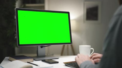 Adult Typing at a Computer with a Green Screen