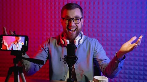 Portrait of a Blogger with Headphones and Condenser Microphone in a Home Studio
