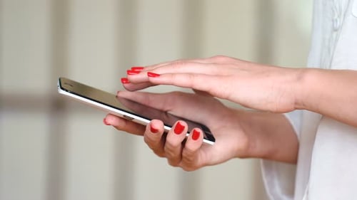 Woman uses phone, red nails