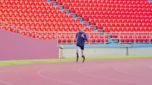 Wide shot and front view of sport man athlete prosthesis legs is jogging on track in the stadium