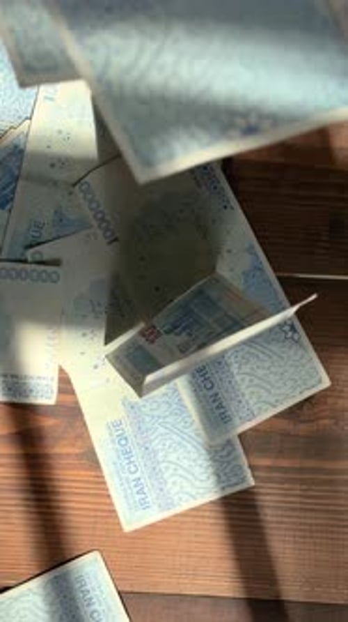 Throw dollar banknote in Iran rial on wooden table shadow bundle money wasting hurl fling forceful c