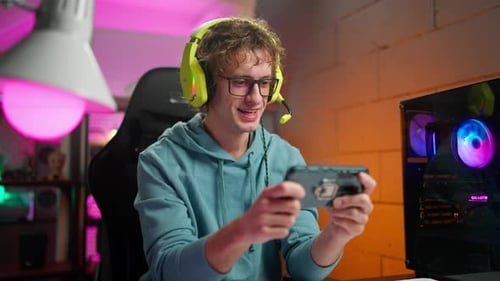 Young Adult Playing Game on Smartphone in Room