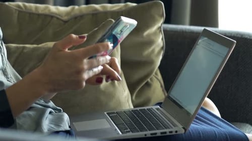 Woman using phone and laptop on couch