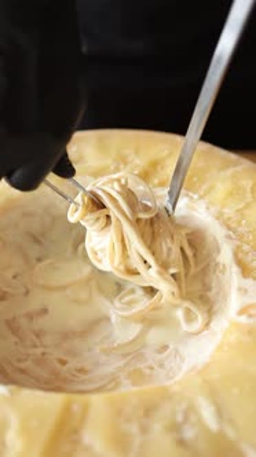Spaghetti Being Prepared Inside of Cheese Wheel