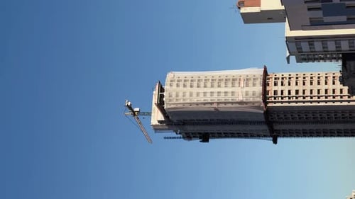 Buildings, working cranes, a city building is being made by two huge white construction cranes, a su