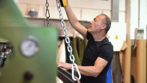 caucasian labor controlling a mechanical Overhead crane for moving heavy stuff inside a factory work