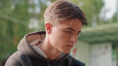 Close-up of handsome young adult in hoodie outdoors