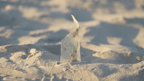 Plastik steckt an einem Strand im Sand. Plastikmüll an einem Strand. Plastikverschmutzung in der Umwelt