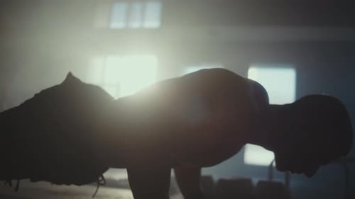 Muscular Man Silhouette Push-Ups in a Smoky Gym