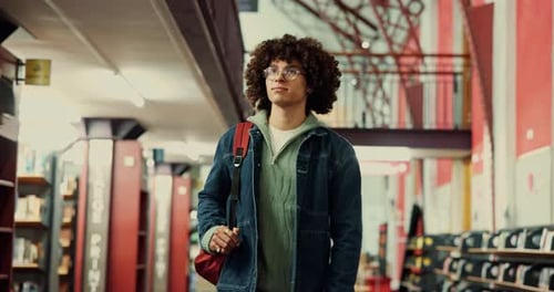 Man, university and student walking in library for study resources, textbook search and knowledge