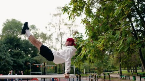 Athletic Man Performing Calisthenics Exercises on Parallel Bars in a Park