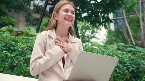 Excited Woman Working on Laptop in Urban Park