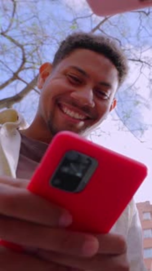 Low Angle View of Happy Young Group of Friends Using Smart Mobile Phones