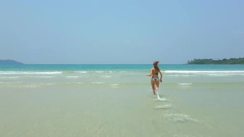 Happy Caucasian Woman Raises Her Hands and Runs Into the Sea on a Tropical Beach