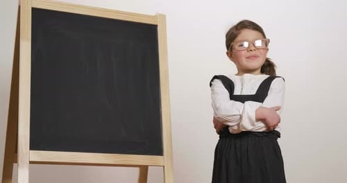 Cute Girl Poses by Blank Chalkboard in Classroom