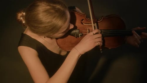 Woman Plays Violin in Dark Setting