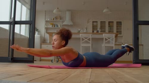 Mujer afroamericana de ajuste deportivo decidida que hace yoga y ejercicios de estiramiento en interiores