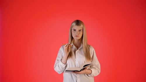 Young Blonde Woman Thinking and Taking Notes, Colorful Studio Portrait