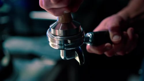 close-up of a barista's hand pressing freshly ground coffee before preparing it in a coffee machine