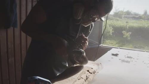 Man Sanding Wood in Open-Air Workshop