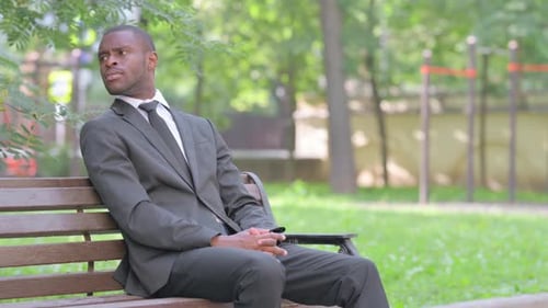 Man in Suit Waiting on Bench in Park