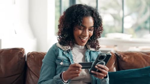 Woman Using Credit Card and Phone on Couch