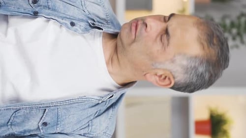 Adult Man Sits with Neck Pain Rubbing Neck