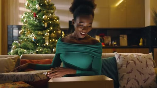 Woman Unwraps Christmas Gift in Living Room