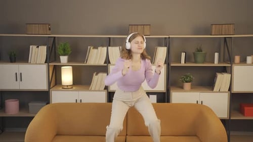 Young Woman Dancing to Music on Sofa