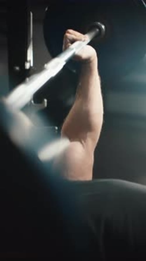 Strong Athlete Performs Bench Press Exercise with Heavy Barbell Showcasing Strength and Dedication