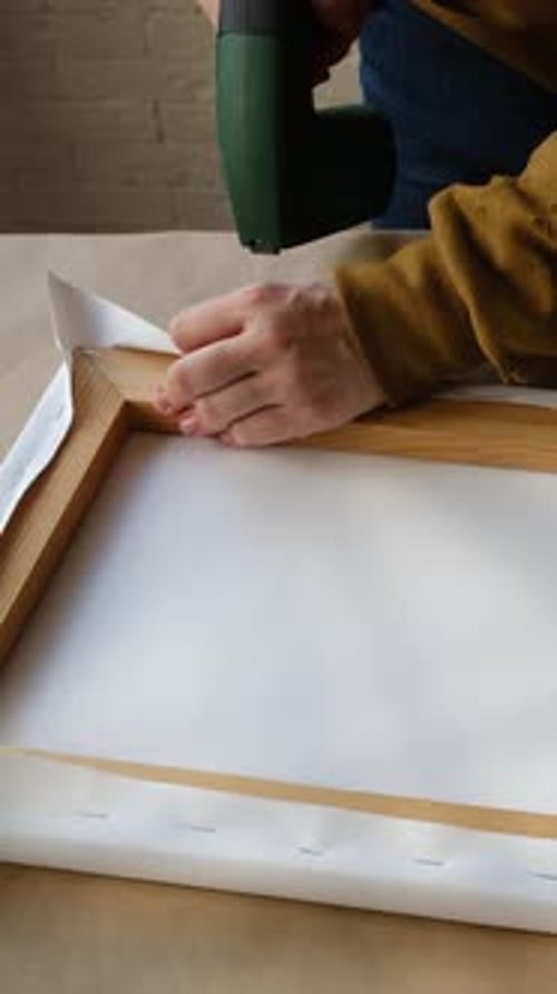 Hand Secures Canvas to Frame with Staple Gun