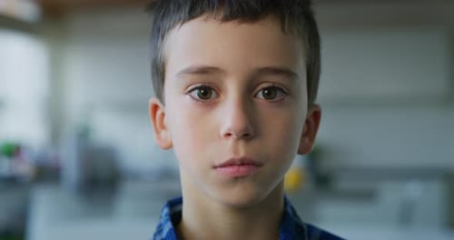 Close up portrait of a little boy with brown eyes looking in the camera on kitchen background. Sho