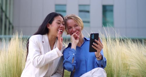 Two Young Diverse Business Women Making a Video Call with Smartphone in a Financial District