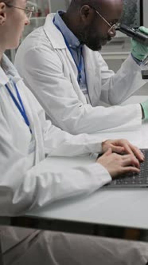 Scientists Working in Lab with Microscope and Computer