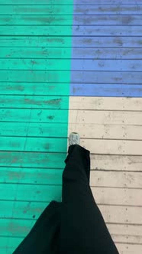 Jambes de femme marchant sur une promenade en bois peinte de couleurs vives