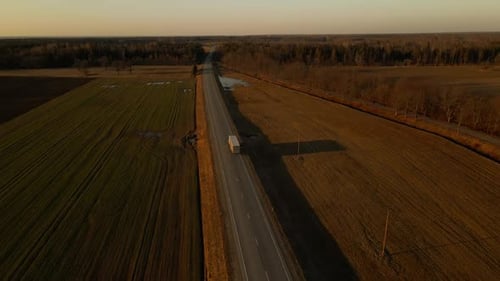 Truck Driving on Asphalt Road Through Grassy Landscape Under the Sky