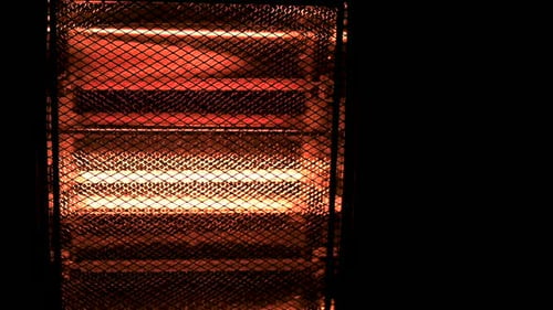 Slowmotion cinematic shot of turning on electric halogen heater in the dark with copyspace